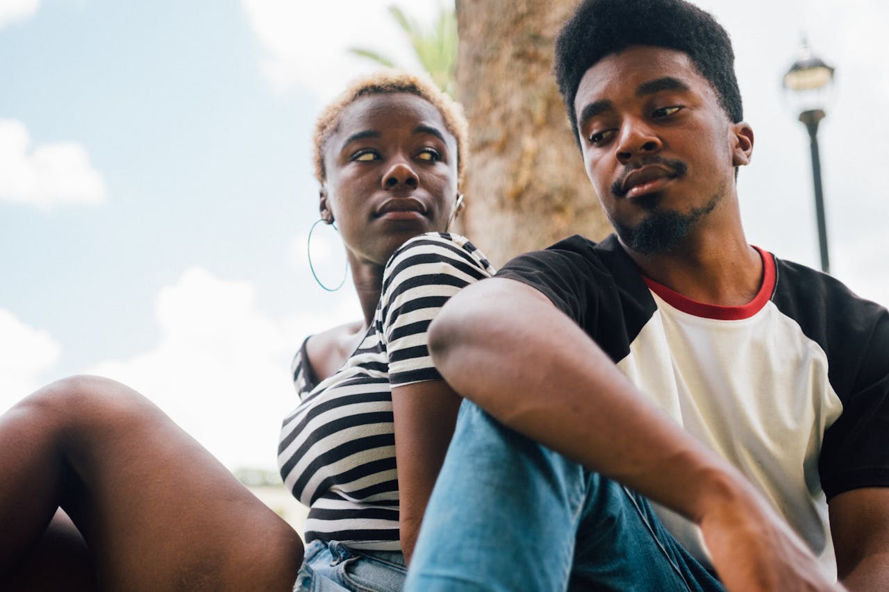 A young couple enjoying a relaxed moment outdoors on a sunny day.